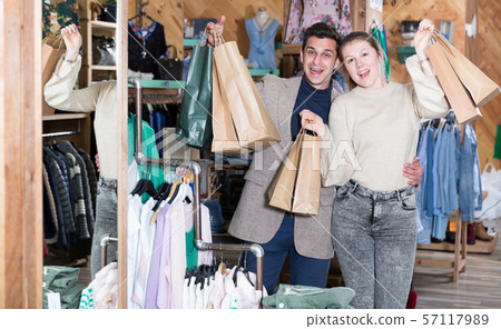 Smiling couple is satisfied of purchases and standing with package Smiling couple is satisfied of purchases and standing with package 57117989