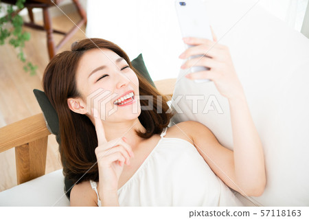 Laughing woman lying down and using smartphone Laughing woman lying down and using smartphone 57118163