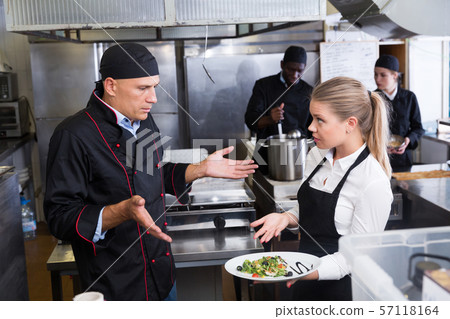 Waitress with dish talking with puzzled chef Waitress with dish talking with puzzled chef 57118164