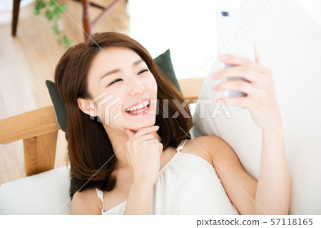 Laughing woman lying down and using smartphone 57118165