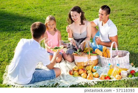 Parents with two teenagers enjoying delicious meal on the picnic 57118393