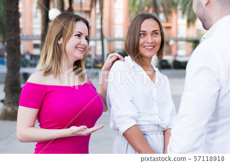 Young male is acquaintance with girls who are walking 57118918