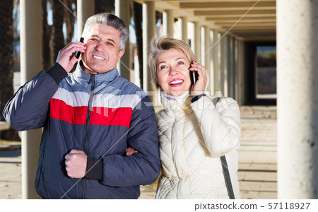 Couple talking by phone outdoors 57118927