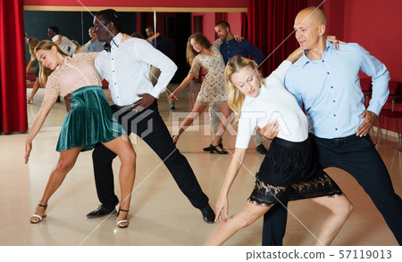 Portrait of positive adult pairs enjoying tango in modern dance hall Portrait of positive adult pairs enjoying tango in modern dance hall 57119013