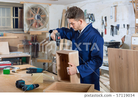 Male worker finishing to drill drawer Male worker finishing to drill drawer 57119034