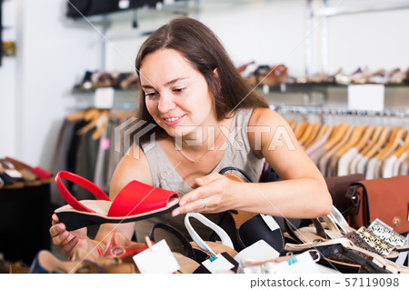 charming female customer selecting shoes in footgear center charming female customer selecting shoes in footgear center 57119098