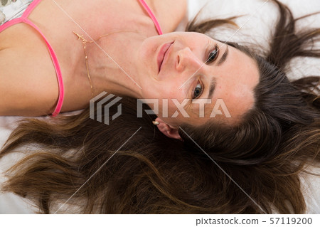 Top view of cute adult woman in sleepwear relaxing in bed in bedroom Top view of cute adult woman in sleepwear relaxing in bed in bedroom 57119200