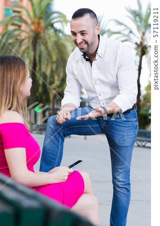 Young male is acquaintance with girl who is sitting on bench 57119211