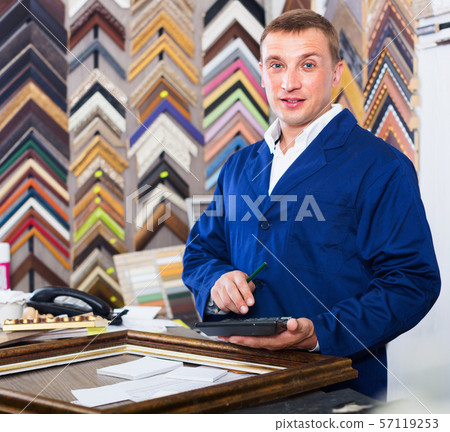 Man worker holding picture frame details on counter Man worker holding picture frame details on counter 57119253