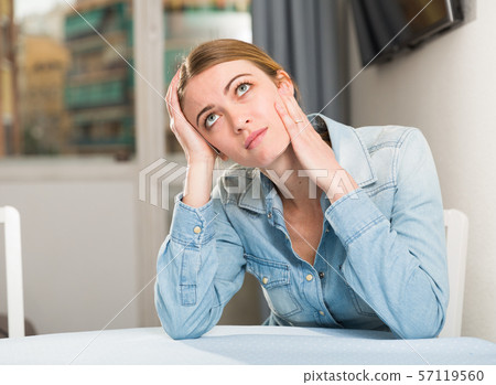 Upset woman sitting at table Upset woman sitting at table 57119560
