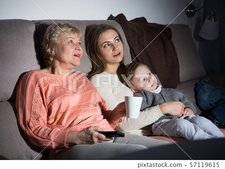 Two women and toddler are enjoying of watch film in evening 57119615