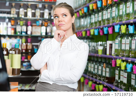Girl thinking about buying new perfume in cosmetics shop Girl thinking about buying new perfume in cosmetics shop 57119710