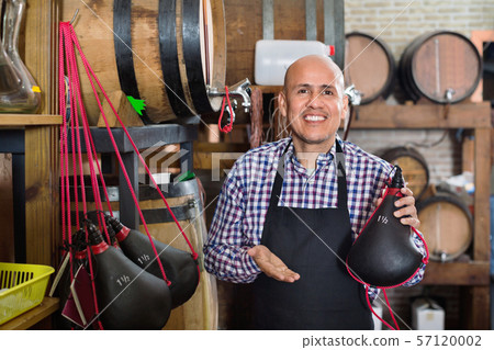 Seller wearing apron and holding spanish bota bag for wine Seller wearing apron and holding spanish bota bag for wine 57120002