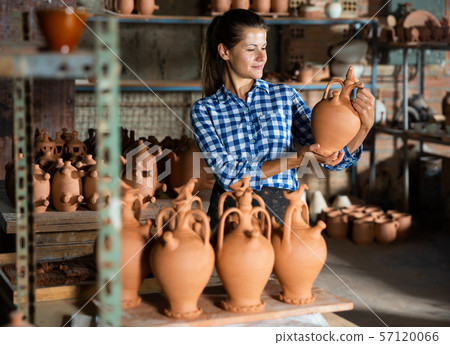 Woman chooses pots clay pots in store warehouse Woman chooses pots clay pots in store warehouse 57120066