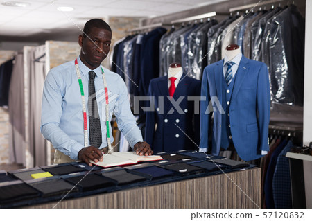 Tailor makes an entry in the book of orders in the studio Tailor makes an entry in the book of orders in the studio 57120832