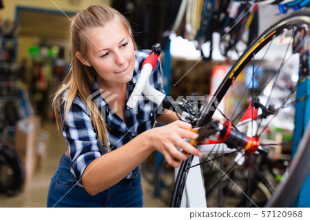 Portrait of girl who is working with pliers and fixing wheels in workshop. Portrait of girl who is working with pliers and fixing wheels in workshop. 57120968