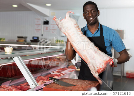 African American male butcher processing carcase of lamb African American male butcher processing carcase of lamb 57121613