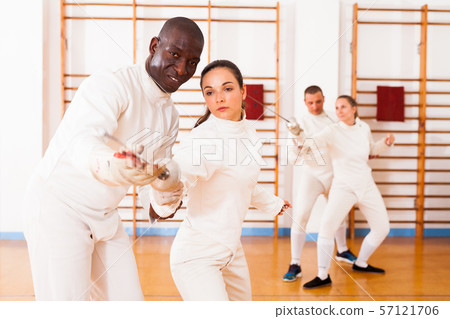 Female fencer practicing movements with african american male trainer Female fencer practicing movements with african american male trainer 57121706