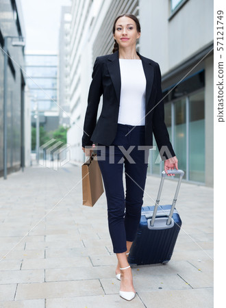 Successful adult businesswoman in suit with suitcase is going to the hotel 57121749