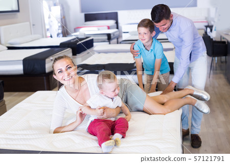 Female with husband and children are choosing comfortable mattress Female with husband and children are choosing comfortable mattress 57121791