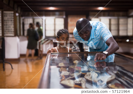 Man and his daughter looking at showcase with exhibits 57121964