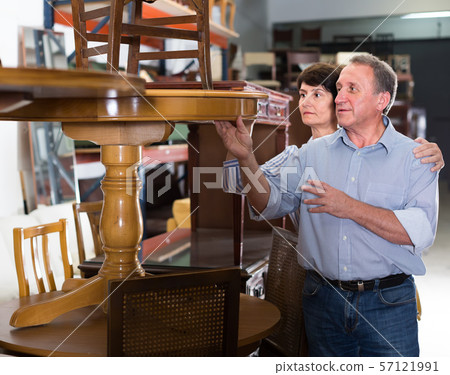 Smiling adult woman with her husband are buying antique table in store Smiling adult woman with her husband are buying antique table in store 57121991