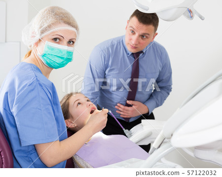 Female stomatologist treating girl with worried father Female stomatologist treating girl with worried father 57122032
