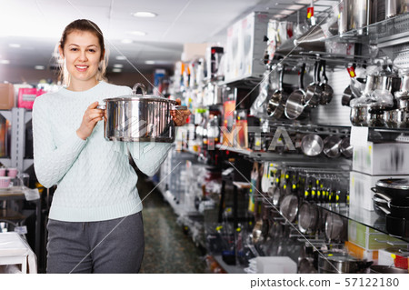 Woman is choosing saucepan for her house in the store. Woman is choosing saucepan for her house in the store. 57122180