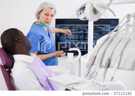 Doctor woman dentist shows patient an x-ray Doctor woman dentist shows patient an x-ray 57122192
