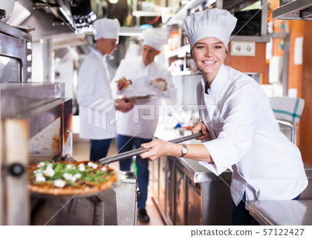 Female chef baking pizza Female chef baking pizza 57122427