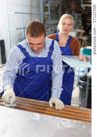 Man and female colleague cleaning glass on washing machine Man and female colleague cleaning glass on washing machine 57122500