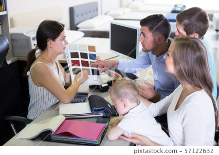 Saleswoman is showing to young family the patterns of mattress fabrics 57122632