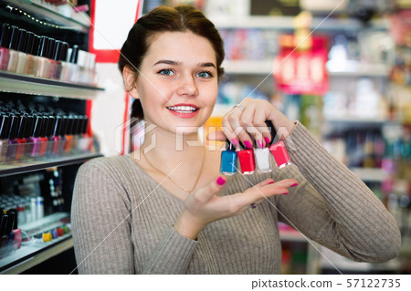 Smiling woman customer deciding on nail polish Smiling woman customer deciding on nail polish 57122735