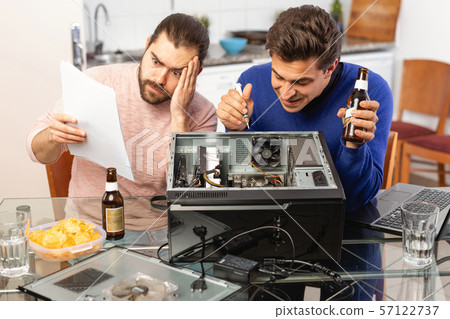 Two men repairing a desktop computer and drink beer Two men repairing a desktop computer and drink beer 57122737