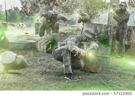 Paintball players aiming and shooting with guns 57122908