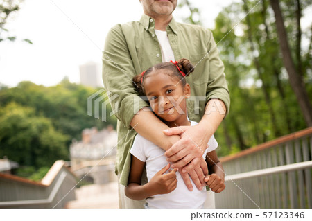 Beautiful dark-eyed daughter with hair buns standing with father 57123346