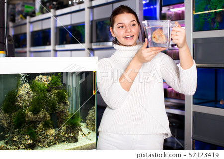 Girl keeps big tropical fish in plastic container Girl keeps big tropical fish in plastic container 57123419