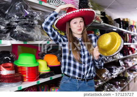 Woman choosing funny headdresses in store 57123727