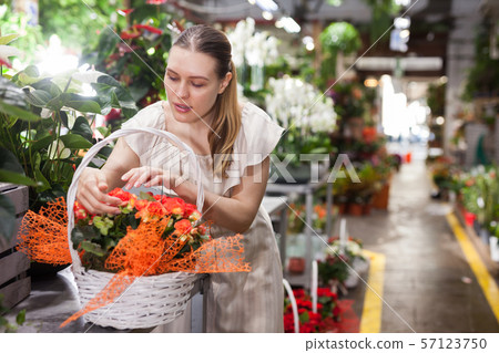 Portrait of woman with basket of red roses in flower shop 57123750
