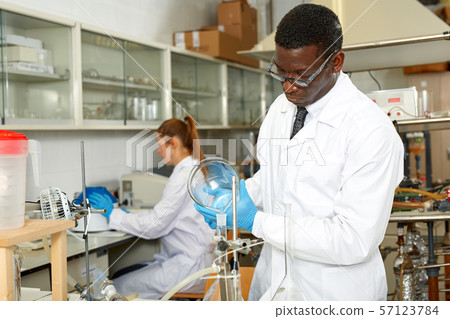 Serious man lab scientist in glasses working with reagents and test tubes Serious man lab scientist in glasses working with reagents and test tubes 57123784