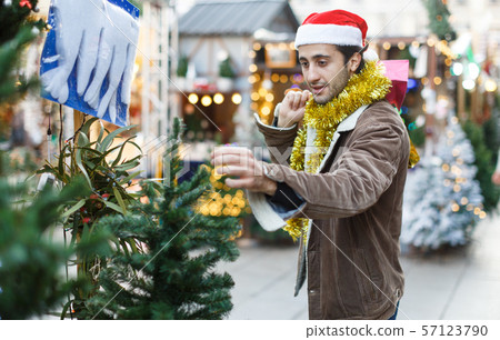 Portrait of joyful man choosing toys and Christmas tree at fair Portrait of joyful man choosing toys and Christmas tree at fair 57123790