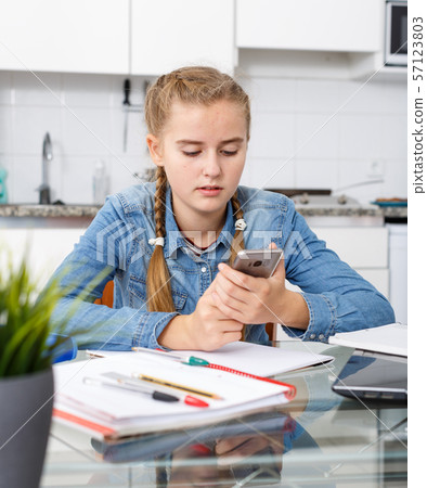 Girl doing her homework using smartphone 57123803