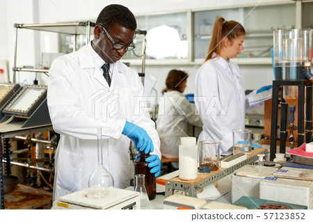 Focused man lab technician in glasses working with reagents and test tubes Focused man lab technician in glasses working with reagents and test tubes 57123852