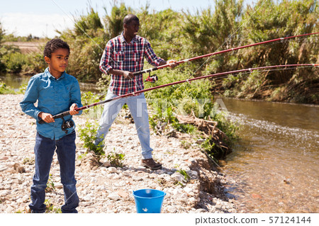 Boy pulling fish from river Boy pulling fish from river 57124144