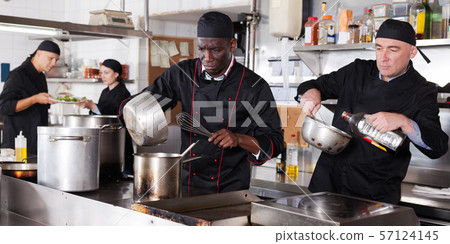 Positive cooks in process of working in kitchen of restaurant Positive cooks in process of working in kitchen of restaurant 57124145