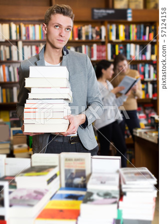 Tired student standing with pile of books Tired student standing with pile of books 57124158