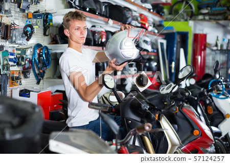 young guy examines a helmet young guy examines a helmet 57124257