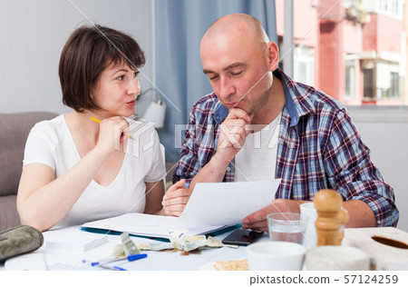 Family couple with financial documents and money at kitchen table Family couple with financial documents and money at kitchen table 57124259