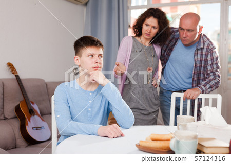 Offended teenager listening to reprimanding from parents Offended teenager listening to reprimanding from parents 57124316