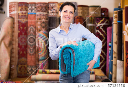 Cheerful woman customer shopping carpet in store Cheerful woman customer shopping carpet in store 57124358